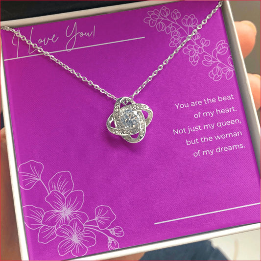 The I Love You CZ Love Knot Necklace is presented in a gift box with a bright purple/fuschia colored background meaningful message card, which reads:  "I Love You! You are the beat of my heart. Not just my queen, but the woman of my dreams."