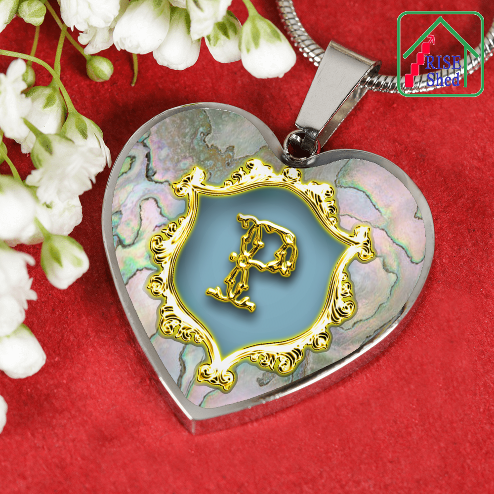 Valentines P Initial Monogram Heart Pendant from Necklace rests against a red surface with white flowers to it's left