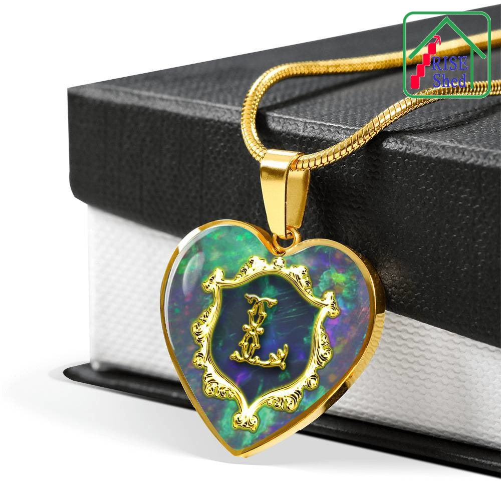 L Initial Monogram Alphabet Heart Pendant And luxury gold finish. Necklace  and pendant are lying draped across a black and white gift box