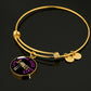 18K yellow gold bangle with a Spoonies - Living For The Good Days pendant lies on a black surface
