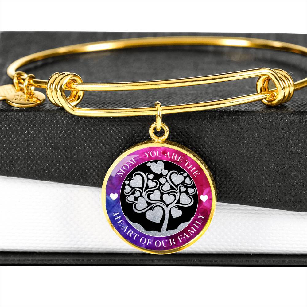 18K Gold Finish version of Mom - You are the Heart of Our Family Stackable Wire Bangle sits on top of black and white gift box with pendant hanging over the side